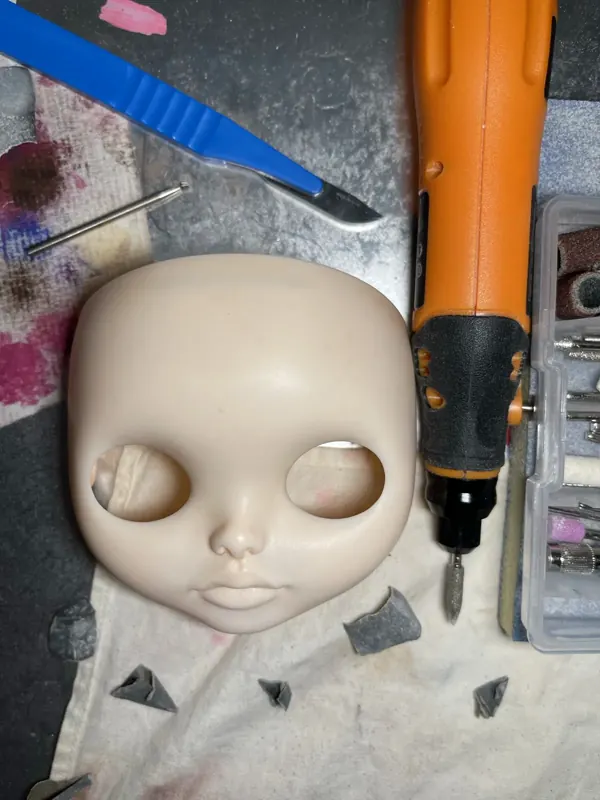 Rostro sin pintar junto a una fresadora y un bisturí